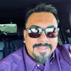 Man wearing sunglasses and a purple shirt inside a vehicle