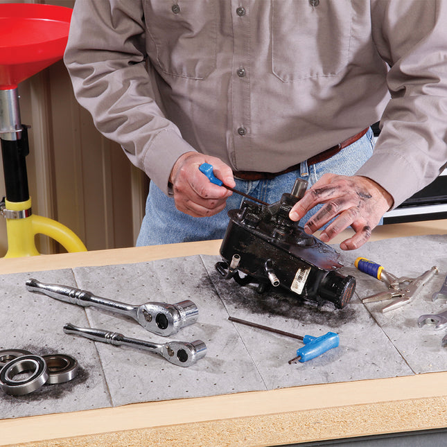 Man standing at work bench working on a mechanical part 