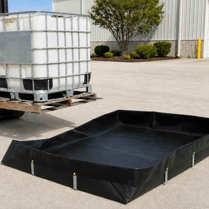 A black L-Bracket Berm  is shown on a concrete lot next to a forklift carrying a white IBC tote container.