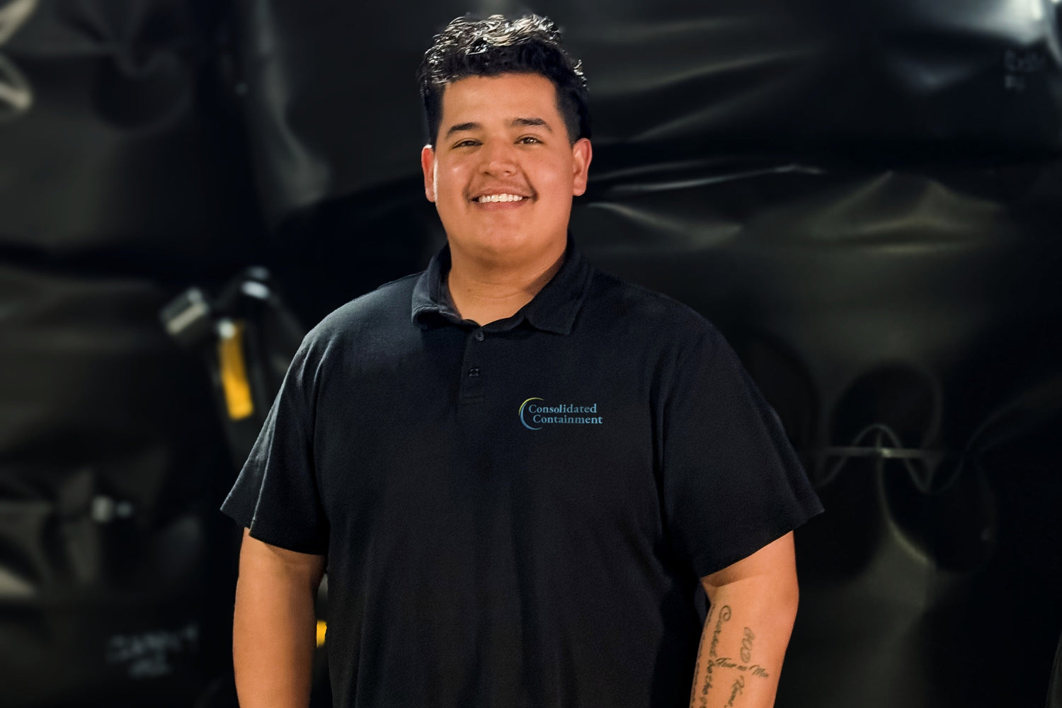 Person wearing a black shirt with a logo in front of a dark background