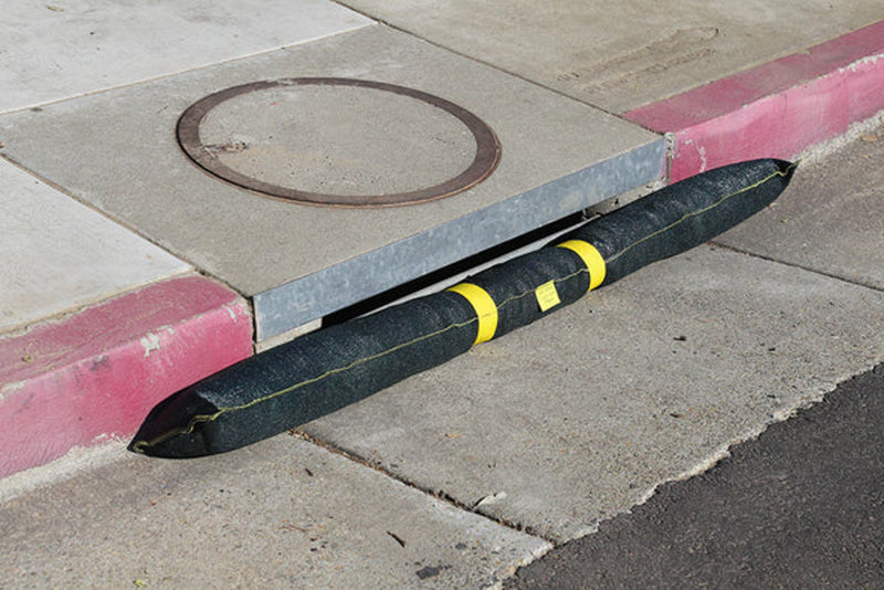 A Spill Bully Curb Inlet Filter resting against a curb in a street side drain